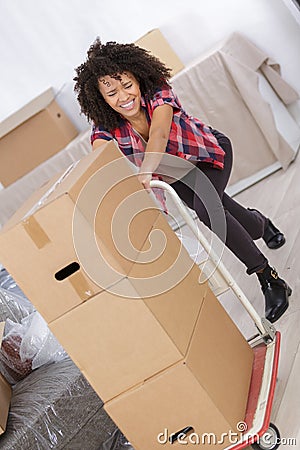 Lady struggling to push trolley loaded with boxes Stock Photo