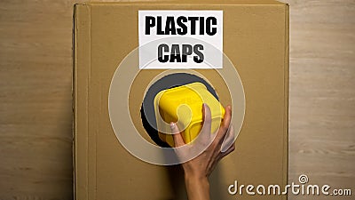 Lady throwing plastic caps in cardboard box collecting reusable material utilize Stock Photo