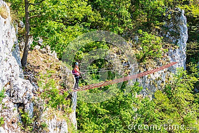 Lady tourist on suspended wooden via ferrata bridge on a route called `Casa Zmeului` in Vadu Crisului, Padurea Craiului mountains Stock Photo