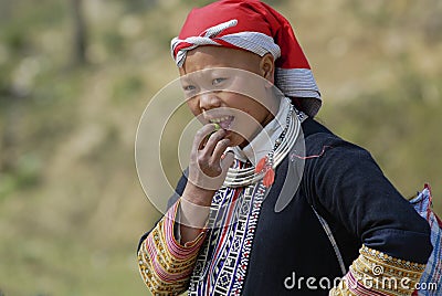 Lady in traditional Red Dzao hill tribe dress eats fruit in Sapa, Vietnam. Editorial Stock Photo