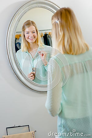 Lady trying on necklace looking in mirror Stock Photo