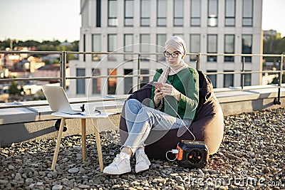 Lady using phone connected to portable power station outside Stock Photo