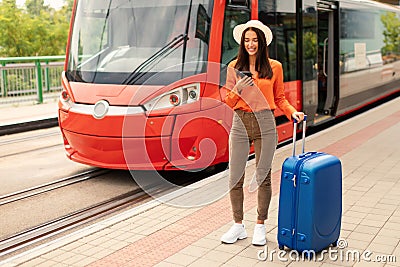 Lady using phone on sidewalk by tram in urban area Stock Photo
