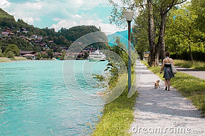 A lady walking her dog on the side of a river Editorial Stock Photo