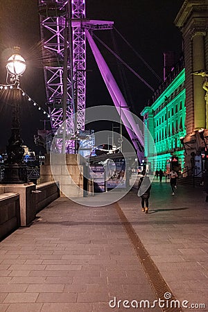 A lady walking by the London Eye at night Editorial Stock Photo
