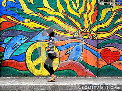 A lady walking past a street wall art Editorial Stock Photo