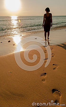 A lady was walking on the sunset and make footprint on the beach Editorial Stock Photo