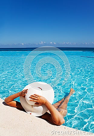 Lady with white hat relaxes in swimming pool Stock Photo