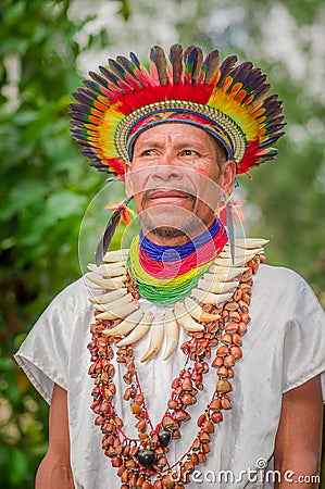 LAGO AGRIO, ECUADOR - NOVEMBER 17, 2016: Close up of a Siona shaman in traditional dress with a feather hat in an Editorial Stock Photo