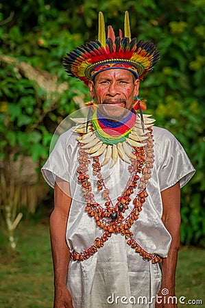 LAGO AGRIO, ECUADOR - NOVEMBER 17, 2016: Siona shaman in traditional dress with a feather hat in an indigenous village Editorial Stock Photo