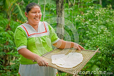 LAGO AGRIO, ECUADOR - NOVEMBER, 17 2016: Woman demonstrates cooking yucca tortillas in an outdoor kitchen in a Siona Editorial Stock Photo