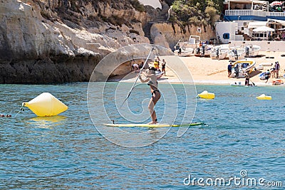 Lagoa, Portugal - July 11, 2020: woman paddle surfing in benagil caves over turquoise waters Editorial Stock Photo
