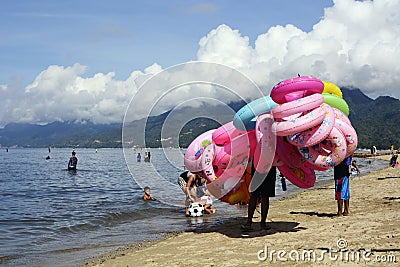 Young man sells and peddles ring lifebuoy on white sand beach Editorial Stock Photo