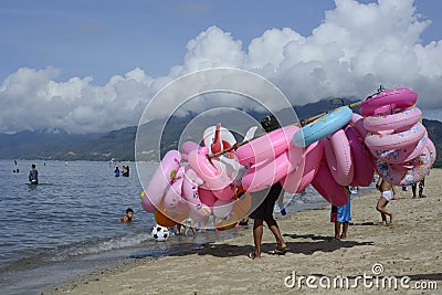 Young man sells and peddles ring lifebuoy on white sand beach Editorial Stock Photo