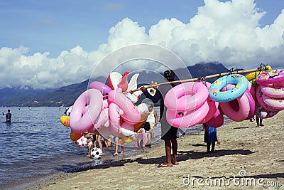 Young man sells and peddles ring lifebuoy on white sand beach Editorial Stock Photo