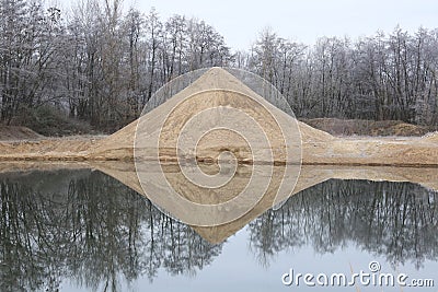 Lake with artificial sand dune and forest in background Stock Photo