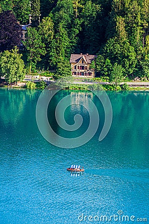 Lake Bled, Slovenia - Traditional Slovenian Pletna boat on Lake Bled with turquoise blue water, weekend house and forest Stock Photo