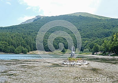 Lake Calamone and a monument on it across the mountain Ventasso on a sunny day. Water reflections. Landscape background. National Stock Photo