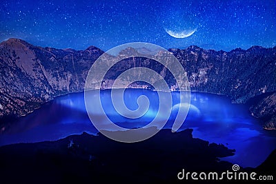 Lake in the crater of a volcano against the background of the starry sky. Reflection of the moonlight on the water. Indonesia. Rin Stock Photo