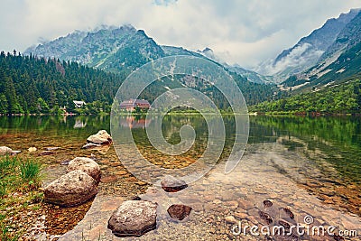 The lake is high in the mountains in the clouds. Hotel near the lake in the mountains. Stock Photo