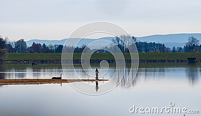 Lake landscape with fisherman on pennisula Stock Photo