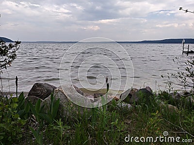 Rocks Lake trees pebbles waves water sky clouds vegetation beach evening view scenic Stock Photo