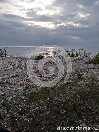 Sunset Rocks Lake trees pebbles waves water sky clouds vegetation beach evening view scenic Stock Photo