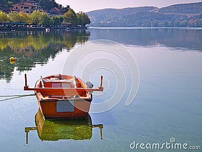 Lake Orestiada, Kastoria, Greece, boat and reflection on calm water. Trees and mountains mirroring on water surface Stock Photo
