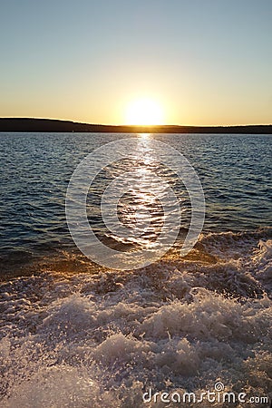 Lake sunset with boat wake waves Stock Photo