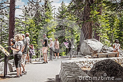 Lake Tahoe - Tourists at overlook checking out map and taking selfies over the Lake with evergreen trees in the Editorial Stock Photo