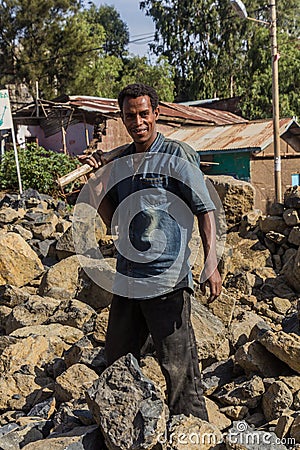 LALIBELA, ETHIOPIA - MARCH 29, 2019: Local worker breaking rocks on a road construction in Lalibela village, Ethiop Editorial Stock Photo