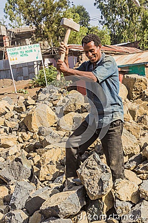 LALIBELA, ETHIOPIA - MARCH 29, 2019: Local worker breaking rocks on a road construction in Lalibela village, Ethiop Editorial Stock Photo