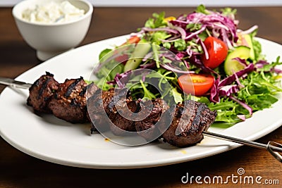 lamb kebabs on white plate, mixed salad on the side Stock Photo