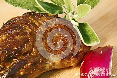 Lamb leg roast slow cooked displayed on wooden cutting board with red onion and fresh mint leaves. Stock Photo