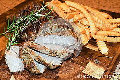 A lamb roast on a wooden board with crinkled fries Stock Photo