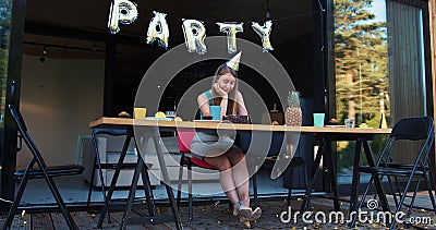 Lame birthday party on quarantine. Sad upset Caucasian young beautiful woman sits alone at home with cake slow motion. Stock Photo