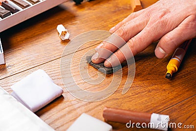 Laminate and parquet restoration repair of wooden furniture sealing scratches and chips. the master polishes the surface close-up Stock Photo