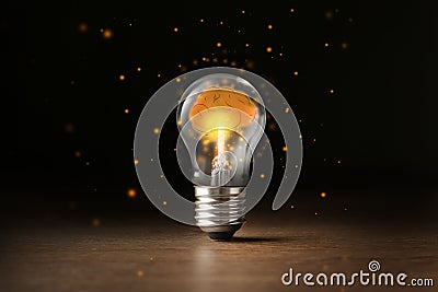 Lamp bulb with shining brain inside on table against black background. Idea generation Stock Photo