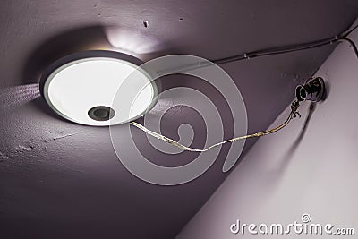 The lamp in the hall of old residential apartment building. Dangerous electrical connection to the lamp. Poor electrical wiring Stock Photo