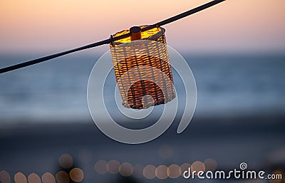 A lamp hangs on a wire against the background of a beach sunset Stock Photo