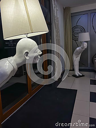 A lamp in the shape of a bowed man with a light bulb and a shade on his head Editorial Stock Photo