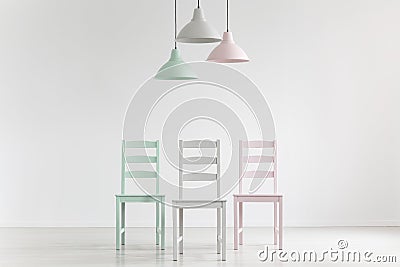 Lamps above chairs in mint, pink and grey color in white empty i Stock Photo