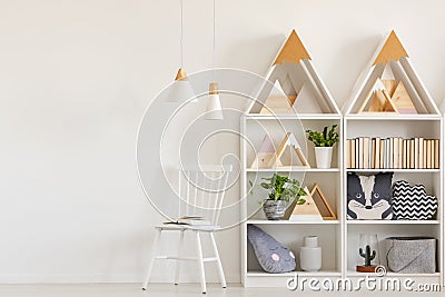 Lamps above white chair next to shelves with triangles in teenag Stock Photo