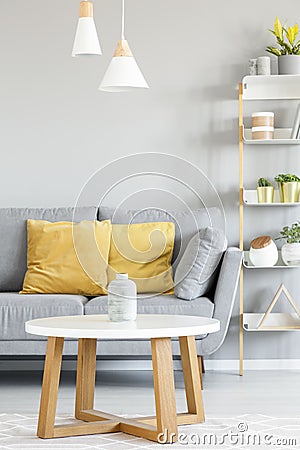 Lamps above wooden table in front of grey sofa with yellow pillo Stock Photo