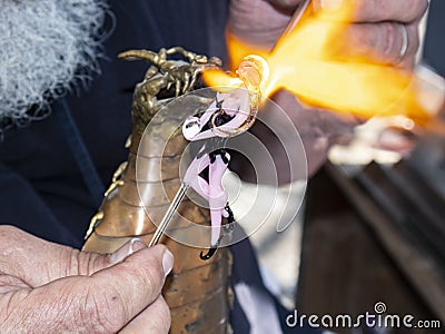 Lampwork - Craftsmans hands forming glass fairy by melting glass with a torch in the form of a dragon Stock Photo