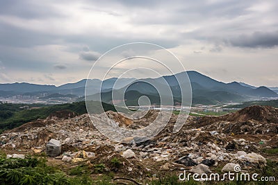 landfill surrounded by natural landscape, with mountains in the background Stock Photo