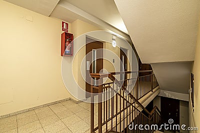 Landing of a residential apartment house with a staircase with light terrazzo floors, red painted metal railings and double Stock Photo