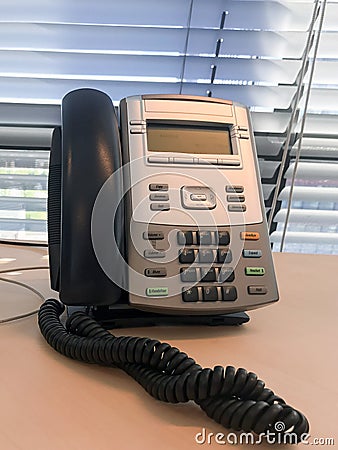 Landline phone on a table with jalousies on a background Stock Photo