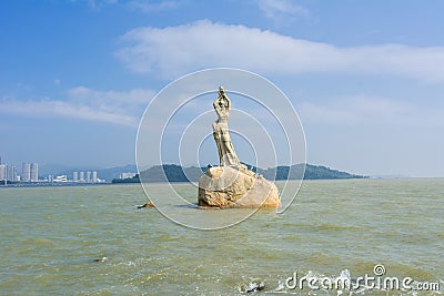 Landmark of Zhuhai city of China. Statue of Fish Woman, fisher girl stature with background of sea, island, and tall buildings Stock Photo