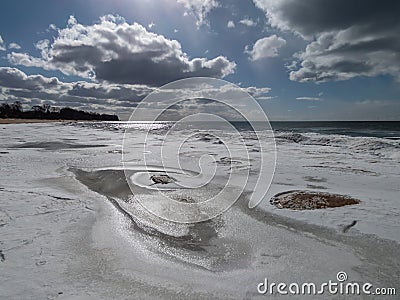 Landscape of Baltic sea and beach with ice and snow formations on the shore in bright sunlight. Frozen ice blocks and sea water in Stock Photo